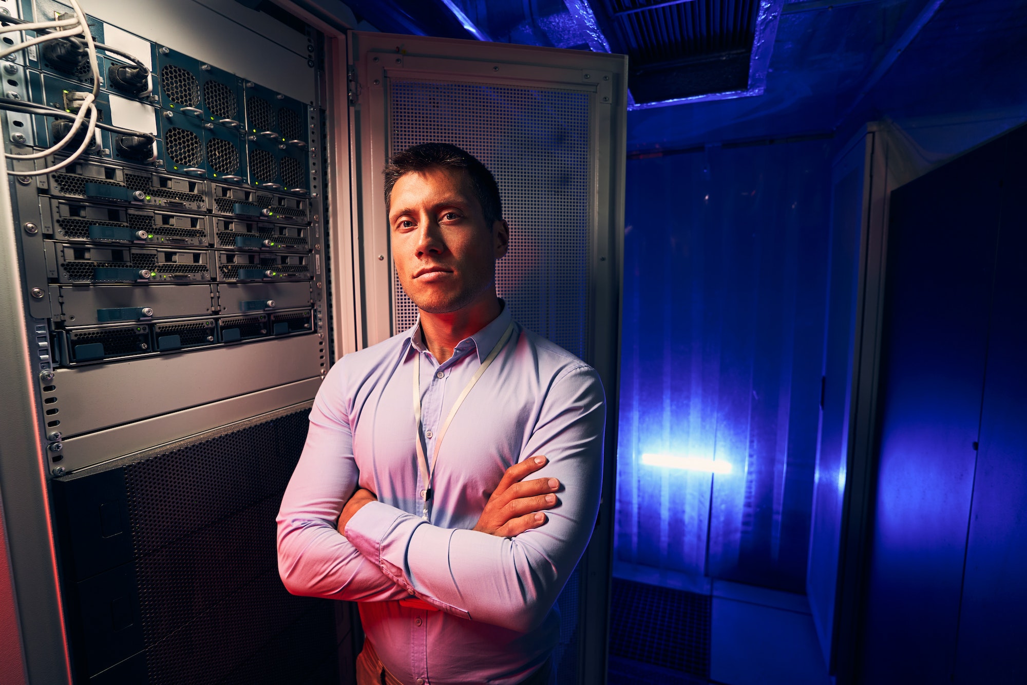 Network administrator standing beside open server rack cabinet